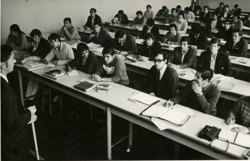 Dictado de clases en una de las aulas de la Facultad de Ingeniería a comienzos de los años setenta. En el lado izquierdo de la imagen se aprecia a la única alumna del aula. Foto: Archivo PUCP. 